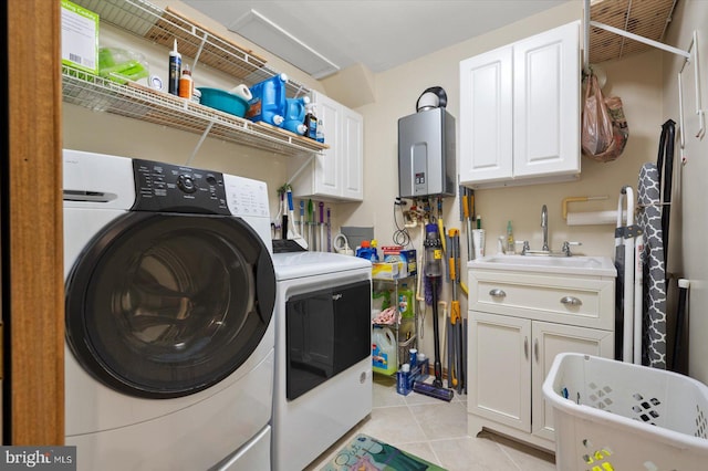 washroom with water heater, light tile patterned floors, cabinets, sink, and washing machine and clothes dryer