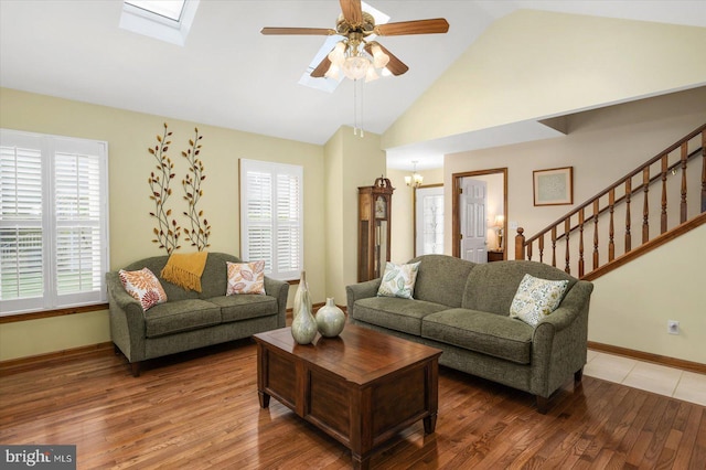 living room with wood-type flooring, ceiling fan, and vaulted ceiling with skylight