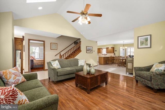 living room featuring ceiling fan with notable chandelier, high vaulted ceiling, and hardwood / wood-style floors