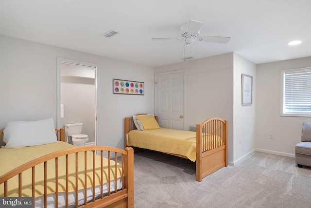 bedroom featuring ceiling fan, light colored carpet, and ensuite bathroom