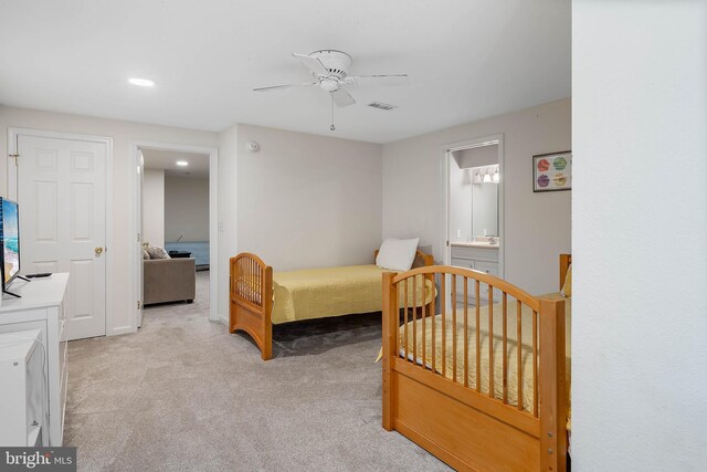 bedroom with ceiling fan, light carpet, and ensuite bathroom