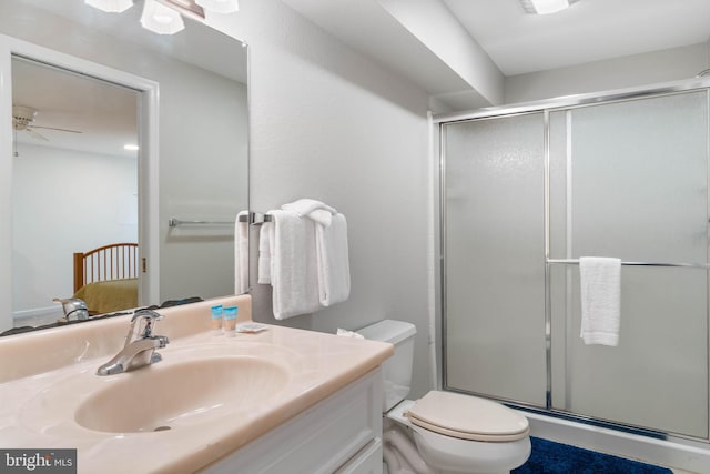 bathroom featuring a shower with shower door, ceiling fan, toilet, and vanity