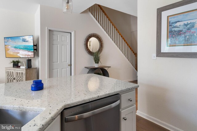 kitchen with light stone countertops, dark hardwood / wood-style flooring, and stainless steel dishwasher