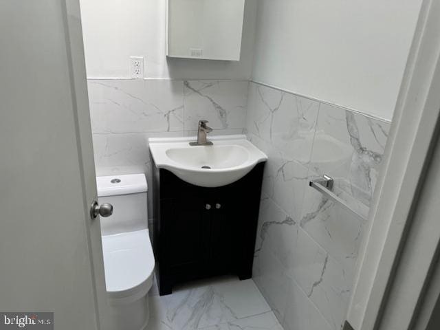 bathroom with tile walls, vanity, and toilet