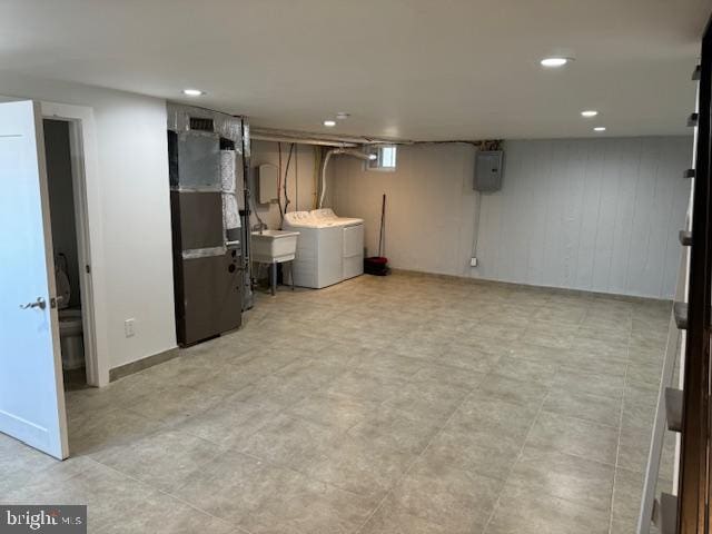 basement featuring heating unit, electric panel, sink, and washing machine and clothes dryer