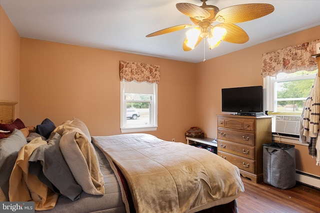 bedroom with multiple windows, a baseboard radiator, ceiling fan, and hardwood / wood-style flooring