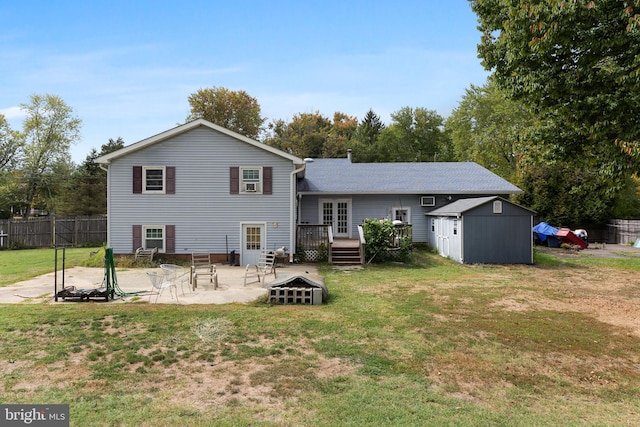 rear view of property featuring a shed, a deck, a lawn, and an outdoor fire pit