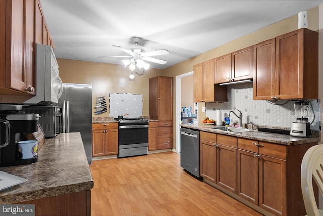 kitchen featuring backsplash, stainless steel appliances, light wood-type flooring, ceiling fan, and sink