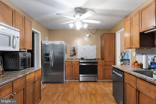 kitchen with light hardwood / wood-style floors, tasteful backsplash, sink, appliances with stainless steel finishes, and ceiling fan