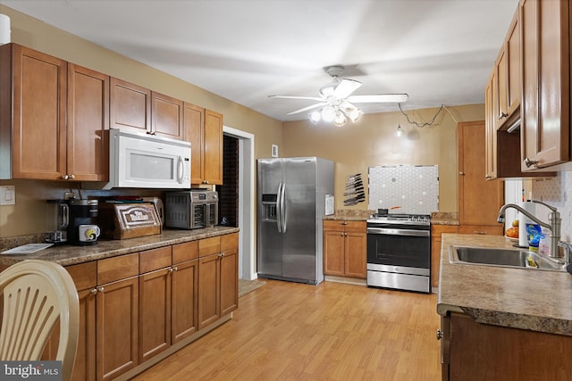 kitchen with backsplash, stainless steel appliances, light wood-type flooring, ceiling fan, and sink