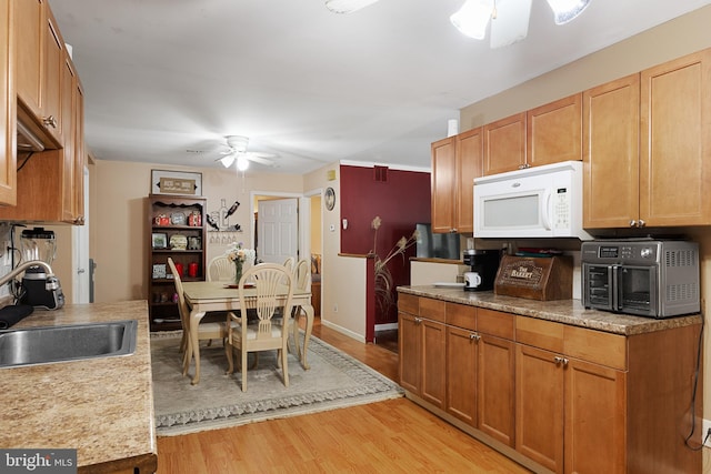 kitchen with sink, ceiling fan, and light hardwood / wood-style flooring