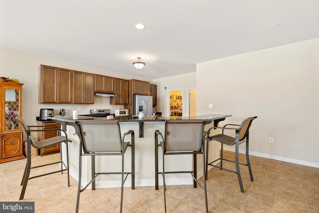 kitchen with a kitchen bar, stainless steel appliances, and a large island with sink