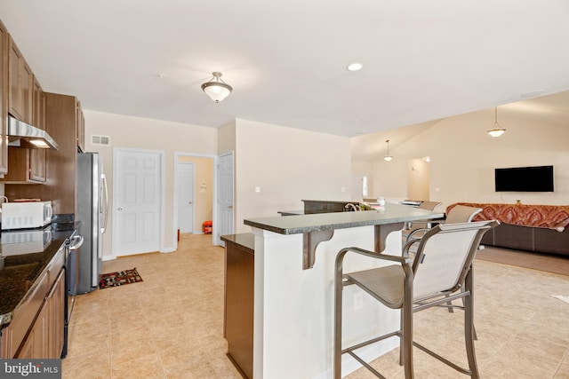 kitchen featuring stainless steel fridge, a breakfast bar, and hanging light fixtures