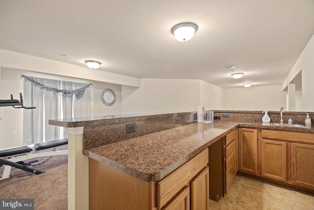 kitchen featuring kitchen peninsula, sink, and dark stone counters