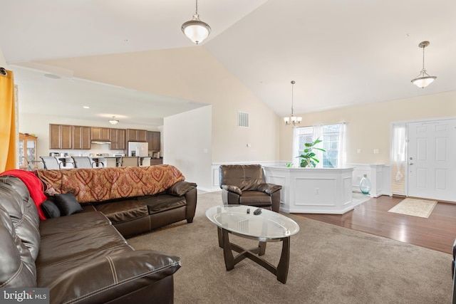 living room featuring dark wood-type flooring, high vaulted ceiling, and an inviting chandelier