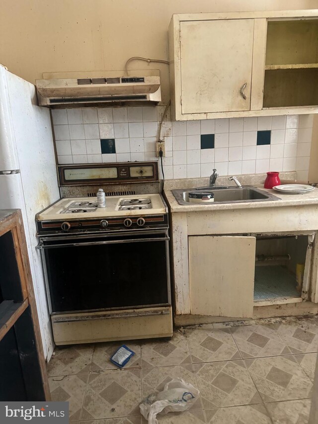 kitchen featuring sink, tasteful backsplash, cream cabinets, range, and range hood