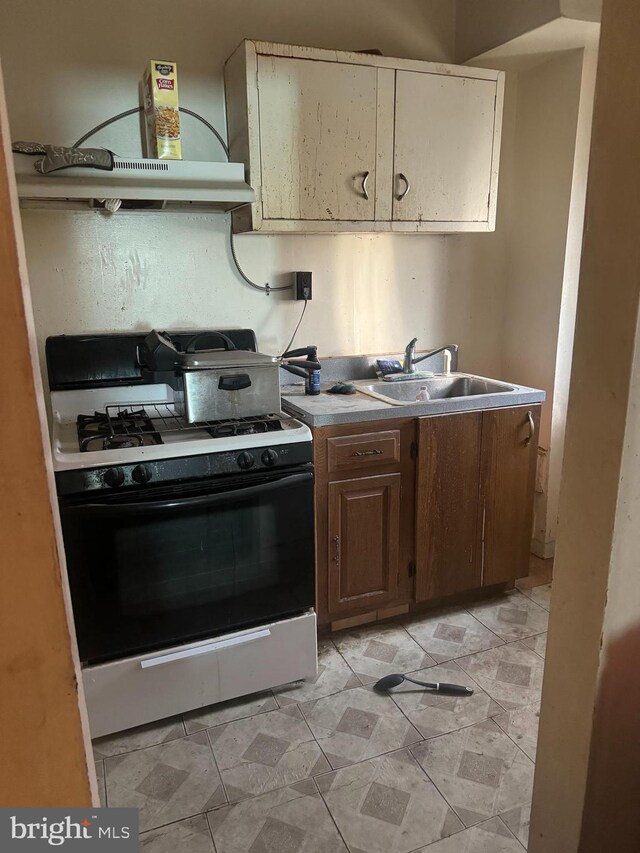 kitchen with white gas range, sink, and extractor fan