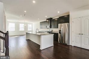 kitchen featuring dark wood-type flooring, stainless steel appliances, an island with sink, and sink