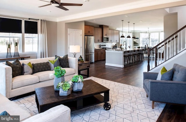 living room featuring hardwood / wood-style floors, ceiling fan with notable chandelier, a wealth of natural light, and ornamental molding