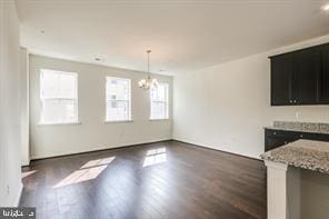 unfurnished dining area featuring a notable chandelier and dark hardwood / wood-style floors