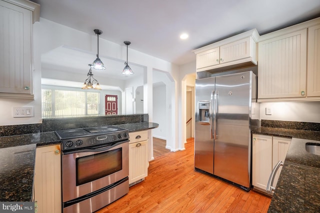 kitchen with hanging light fixtures, light hardwood / wood-style flooring, appliances with stainless steel finishes, dark stone countertops, and an inviting chandelier