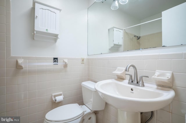 bathroom with walk in shower, sink, tile walls, and toilet