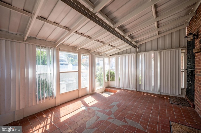 unfurnished sunroom with vaulted ceiling with beams