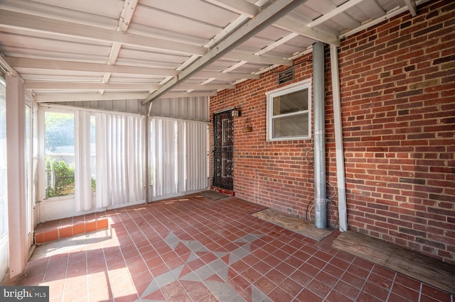 unfurnished sunroom featuring lofted ceiling with beams