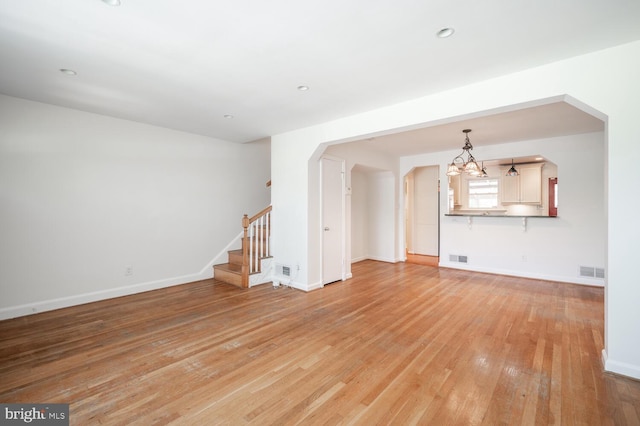 unfurnished living room with light hardwood / wood-style floors and an inviting chandelier