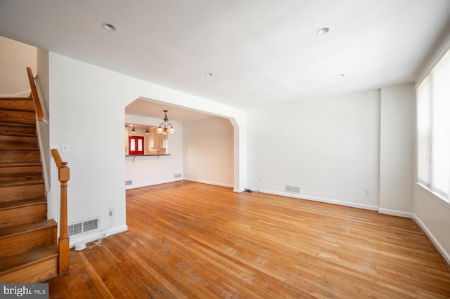 unfurnished living room featuring an inviting chandelier and hardwood / wood-style flooring