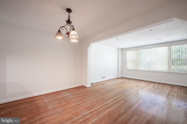 spare room with a chandelier and light hardwood / wood-style floors