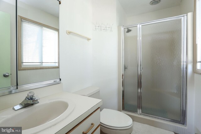 bathroom with a shower with door, vanity, and toilet