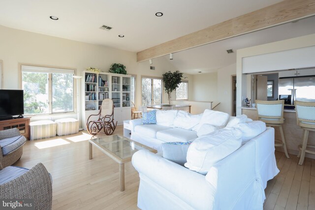 living room featuring beamed ceiling, plenty of natural light, and light hardwood / wood-style floors