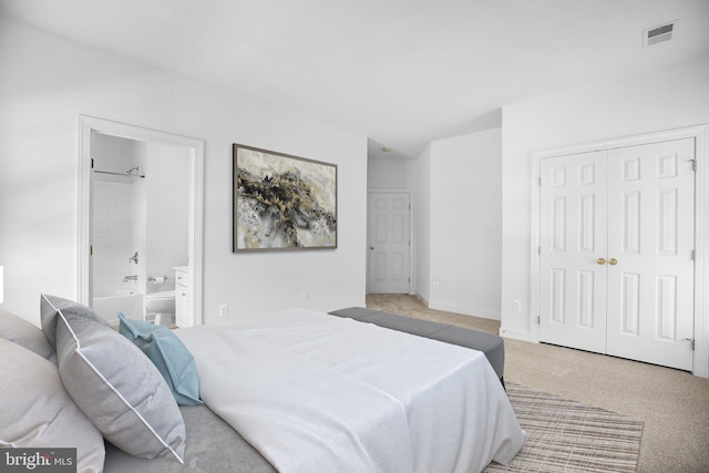 bedroom with connected bathroom and light colored carpet