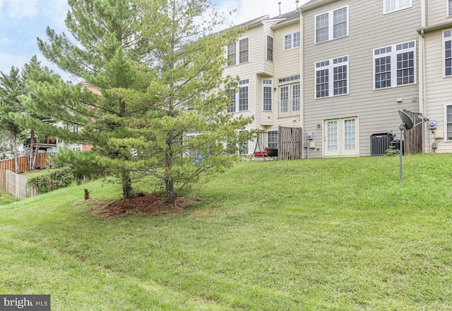 back of property with central AC unit and a lawn