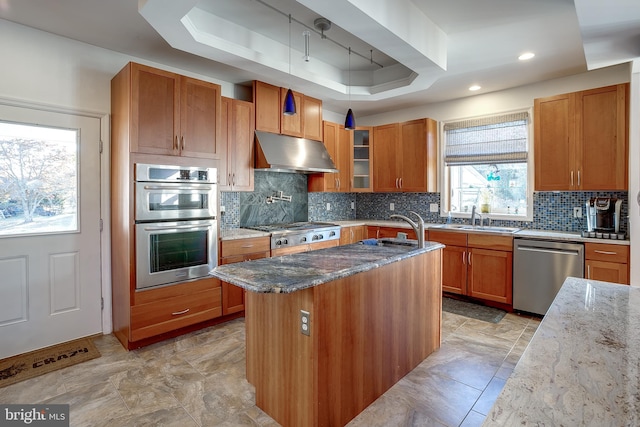 kitchen featuring range hood, light stone counters, stainless steel appliances, and decorative backsplash