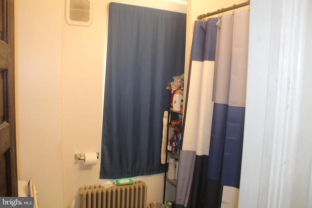 bathroom with a shower with curtain and radiator heating unit