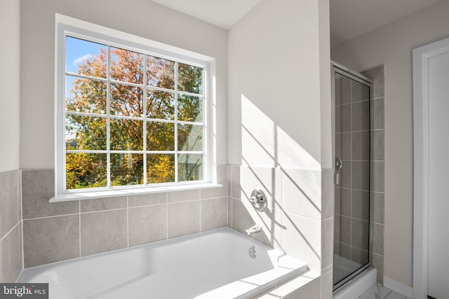 bathroom with shower with separate bathtub and plenty of natural light