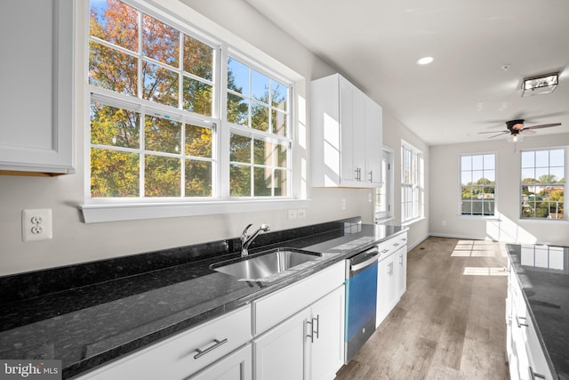 kitchen featuring white cabinets, stainless steel dishwasher, dark stone countertops, light hardwood / wood-style floors, and sink