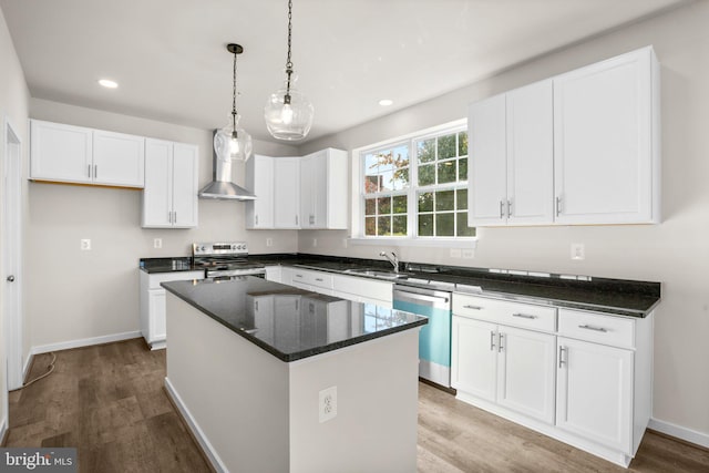 kitchen with white cabinetry, wall chimney range hood, appliances with stainless steel finishes, and a center island