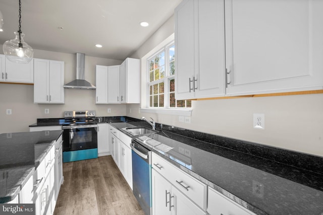 kitchen featuring white cabinetry, wall chimney range hood, appliances with stainless steel finishes, and dark stone counters