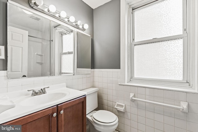 bathroom featuring vanity, tile walls, and toilet