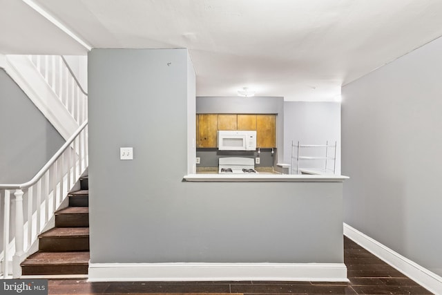 kitchen with kitchen peninsula, dark wood-type flooring, and white appliances