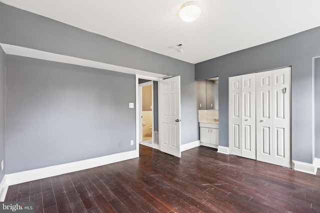 unfurnished bedroom featuring connected bathroom and dark hardwood / wood-style floors