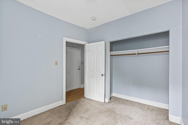 unfurnished bedroom featuring a closet and light colored carpet