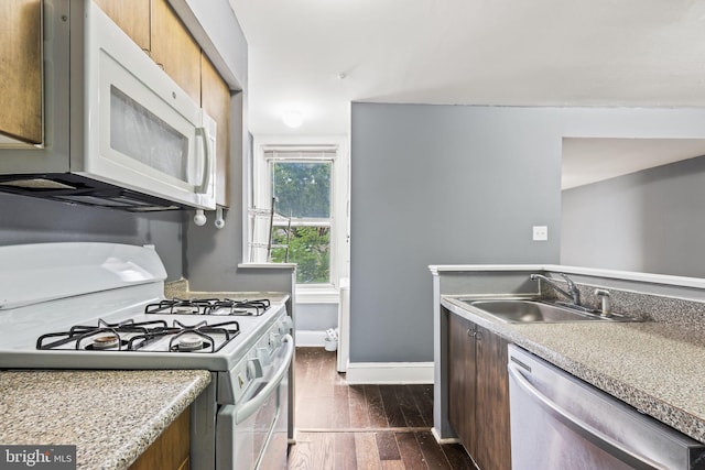 kitchen featuring white appliances, dark wood-type flooring, and sink