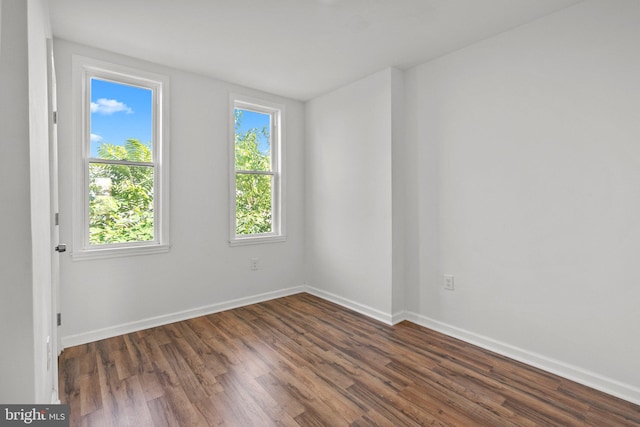 unfurnished room with a healthy amount of sunlight and dark wood-type flooring