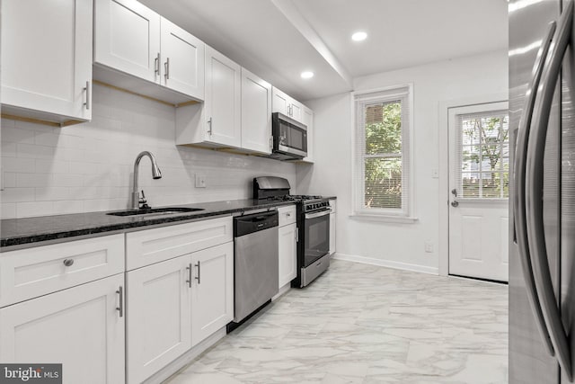 kitchen featuring dark stone counters, white cabinetry, sink, and stainless steel appliances