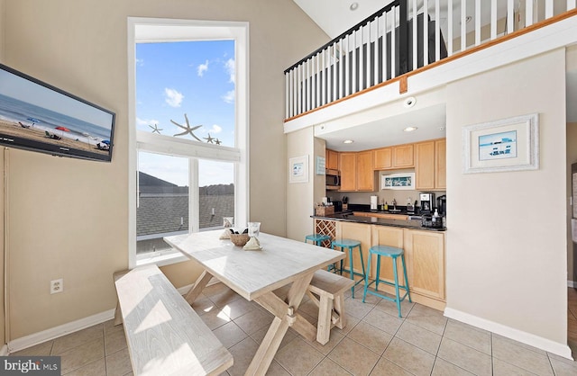 dining room with a water view, a towering ceiling, and light tile patterned floors