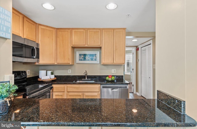 kitchen featuring sink, dark stone counters, and appliances with stainless steel finishes